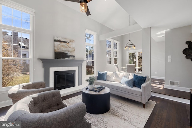 living room featuring a high ceiling, wood-type flooring, visible vents, and a healthy amount of sunlight