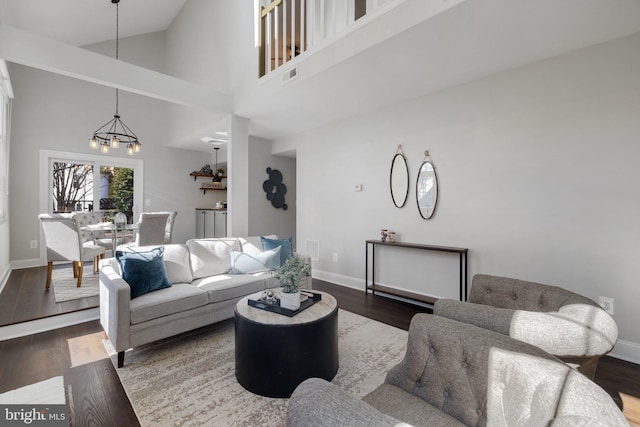 living room with dark wood-style flooring, visible vents, and baseboards