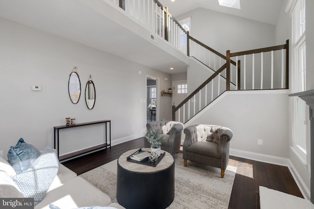 living room featuring visible vents, baseboards, wood finished floors, stairs, and high vaulted ceiling