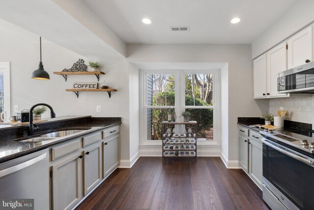 kitchen featuring dark wood-style floors, open shelves, stainless steel appliances, visible vents, and a sink