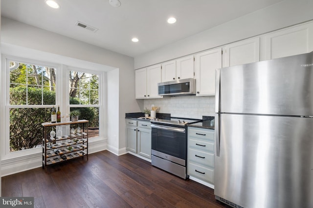 kitchen featuring tasteful backsplash, visible vents, dark wood-type flooring, stainless steel appliances, and white cabinetry