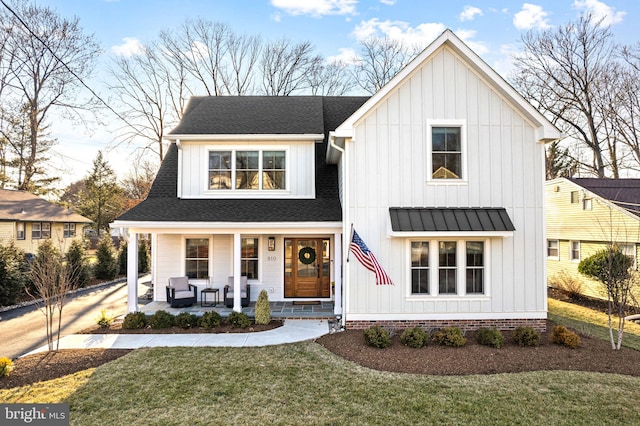 modern farmhouse with metal roof, covered porch, roof with shingles, a front lawn, and board and batten siding