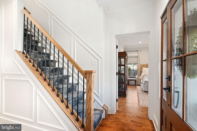 foyer featuring baseboards, stairway, wood finished floors, and crown molding