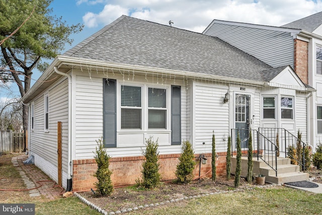 view of front of home with brick siding and roof with shingles