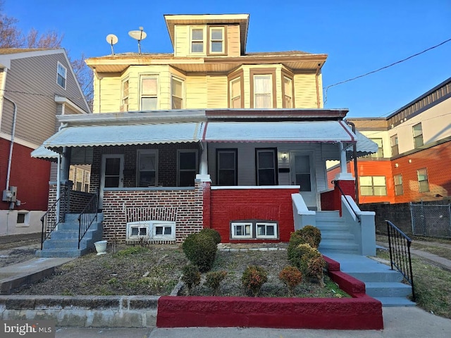 american foursquare style home with covered porch and brick siding