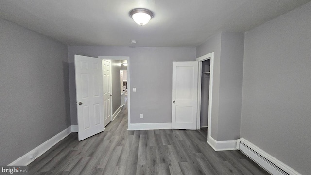 unfurnished bedroom with baseboards, baseboard heating, and dark wood-style flooring