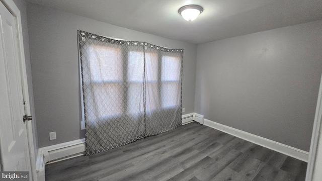 spare room with dark wood-style floors, baseboard heating, and baseboards