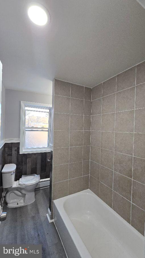 full bath featuring a washtub, a shower, wood finished floors, and toilet