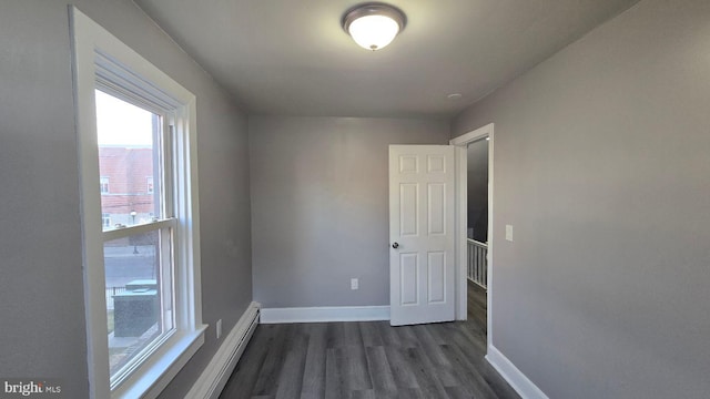 spare room with dark wood-style floors, baseboards, and a baseboard heating unit