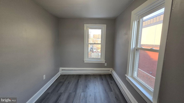 spare room featuring dark wood-style floors, a baseboard radiator, and baseboards