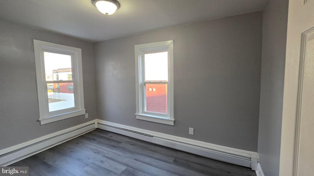 unfurnished room with dark wood-type flooring, a baseboard radiator, and a healthy amount of sunlight