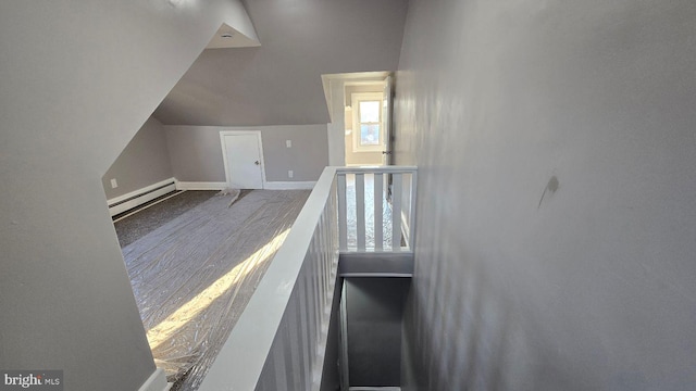 stairs featuring lofted ceiling, baseboards, and a baseboard heating unit