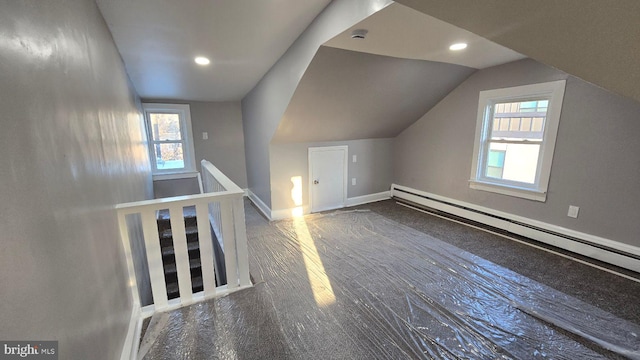 additional living space featuring vaulted ceiling, plenty of natural light, a baseboard radiator, and baseboards