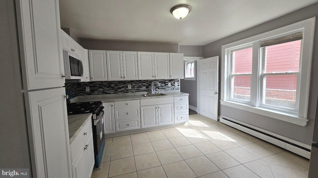 kitchen featuring decorative backsplash, stainless steel microwave, black range with gas stovetop, baseboard heating, and a sink