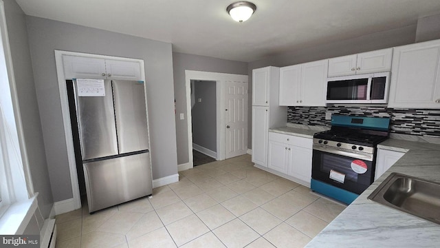 kitchen featuring stainless steel appliances, a sink, backsplash, and light tile patterned floors