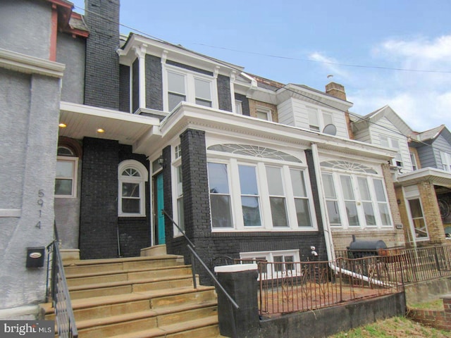 multi unit property featuring entry steps, brick siding, fence, and a chimney