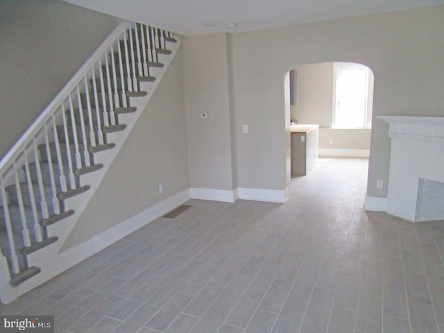 interior space with arched walkways, wood finished floors, visible vents, and baseboards