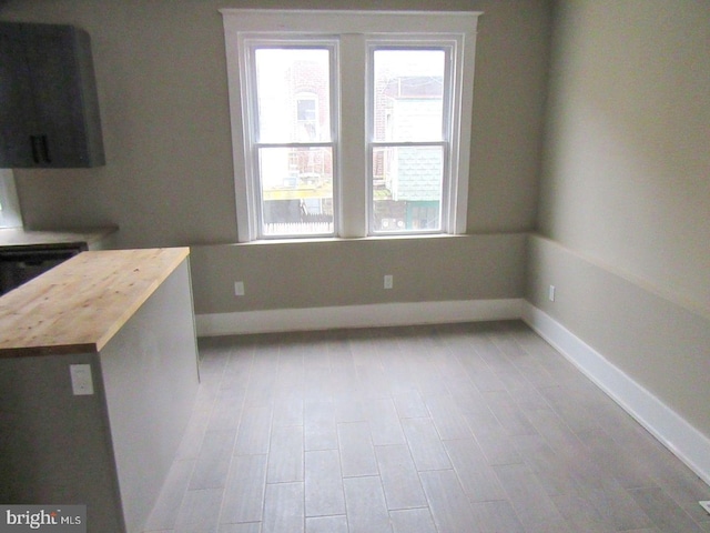 unfurnished dining area featuring light wood-style flooring and baseboards