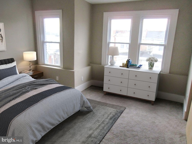 bedroom with baseboards and light colored carpet