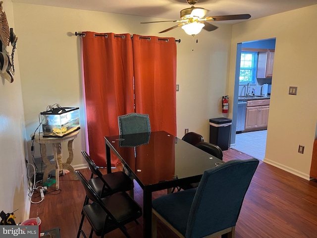 dining space with wood finished floors, a ceiling fan, and baseboards