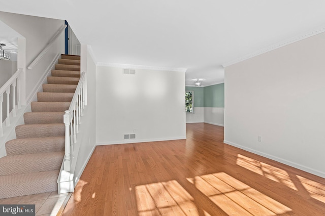 interior space with visible vents, crown molding, baseboards, and wood finished floors