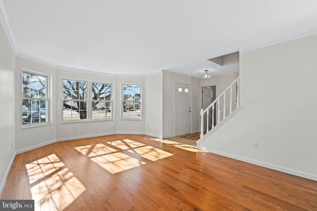 unfurnished room with hardwood / wood-style flooring, stairway, plenty of natural light, and baseboards