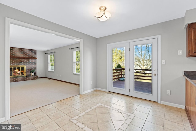 doorway with light tile patterned flooring, a fireplace, baseboards, and light carpet