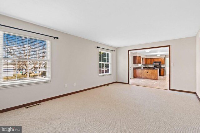 unfurnished living room featuring visible vents, light carpet, and baseboards