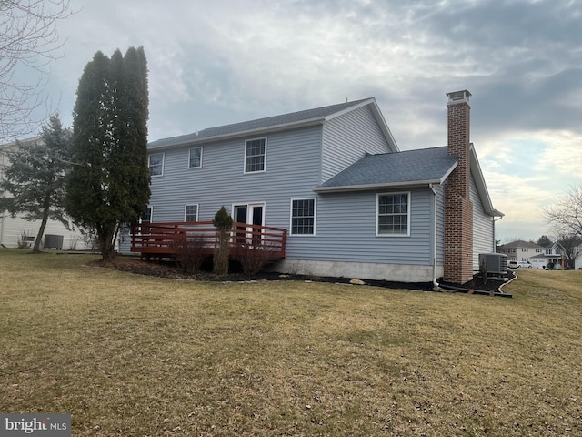 rear view of house with a lawn, central AC, roof with shingles, a wooden deck, and a chimney