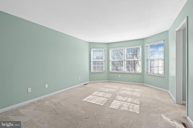 carpeted empty room with a wealth of natural light and baseboards