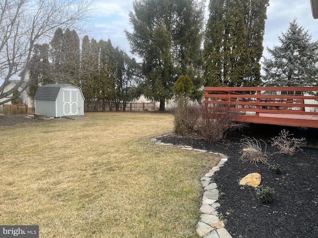 view of yard with a shed, a wooden deck, an outdoor structure, and fence