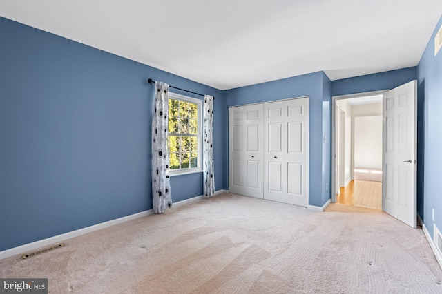 unfurnished bedroom with carpet flooring, baseboards, visible vents, and a closet