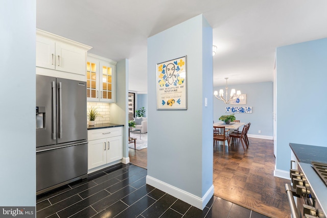 kitchen featuring baseboards, high quality appliances, glass insert cabinets, white cabinetry, and backsplash