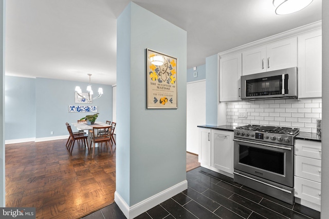 kitchen featuring appliances with stainless steel finishes, dark countertops, white cabinets, and decorative backsplash