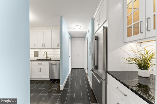 kitchen with backsplash, appliances with stainless steel finishes, glass insert cabinets, white cabinetry, and a sink