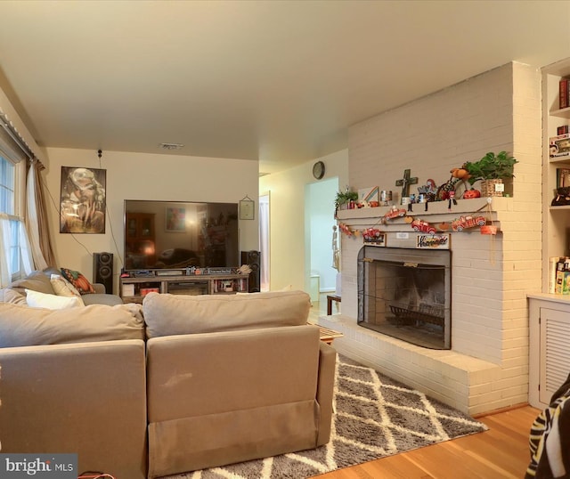 living area featuring a fireplace, wood finished floors, and visible vents