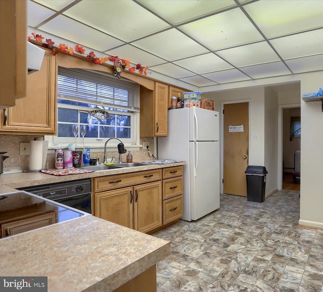 kitchen featuring light countertops, a drop ceiling, a sink, and freestanding refrigerator