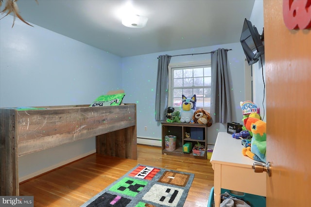 bedroom featuring a baseboard heating unit and wood finished floors