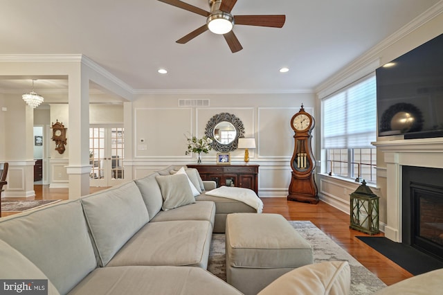 living room with a fireplace with flush hearth, visible vents, a decorative wall, and crown molding