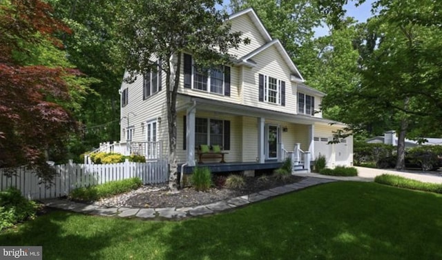 view of front of home with covered porch, fence, and a front lawn