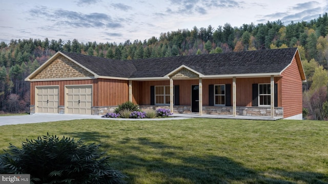 view of front facade featuring a garage, driveway, a view of trees, stone siding, and a front lawn