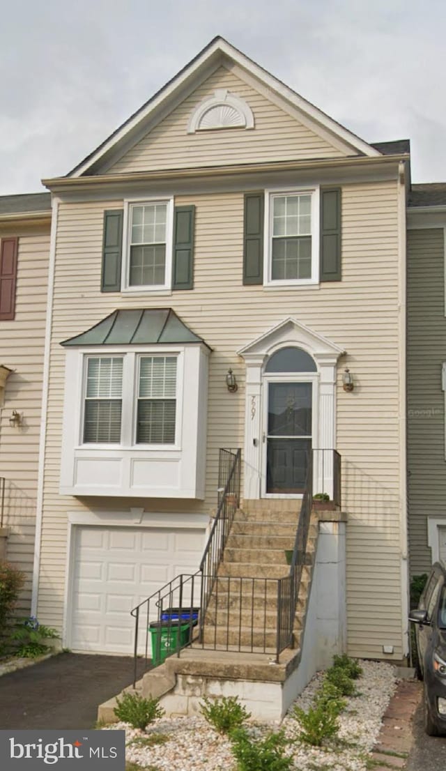 townhome / multi-family property featuring a garage and aphalt driveway