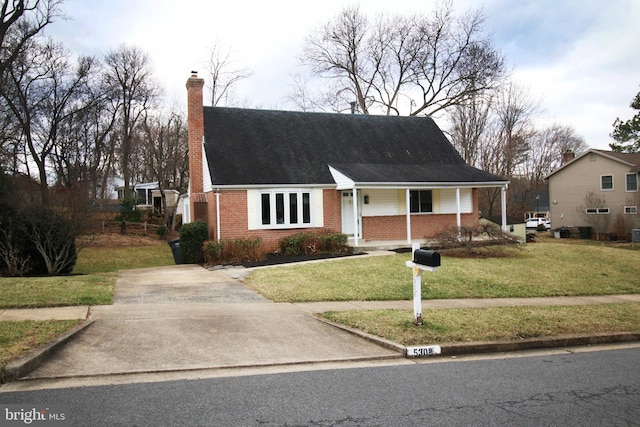 view of front of home with covered porch, brick siding, a chimney, and a front lawn