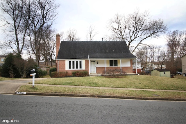 view of front facade featuring a storage unit, brick siding, an outdoor structure, a front lawn, and a chimney