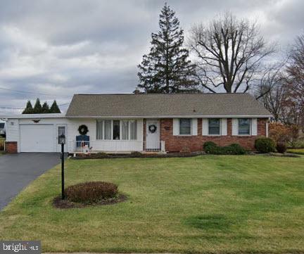 ranch-style home with an attached garage, brick siding, driveway, and a front lawn