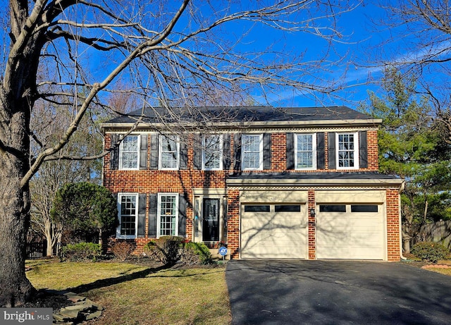 colonial home featuring a front lawn, aphalt driveway, and brick siding