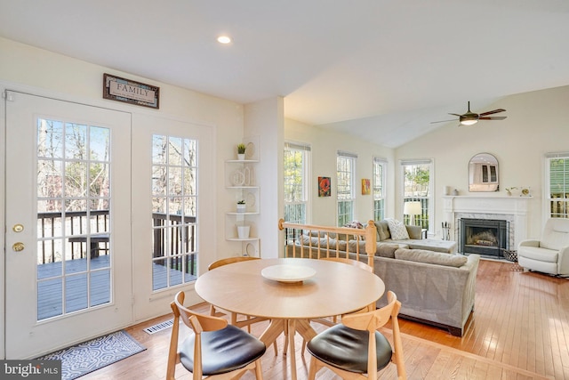 dining space featuring light wood-type flooring, visible vents, vaulted ceiling, and a wealth of natural light