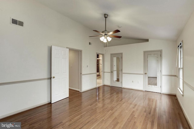 unfurnished bedroom with vaulted ceiling, wood finished floors, and visible vents