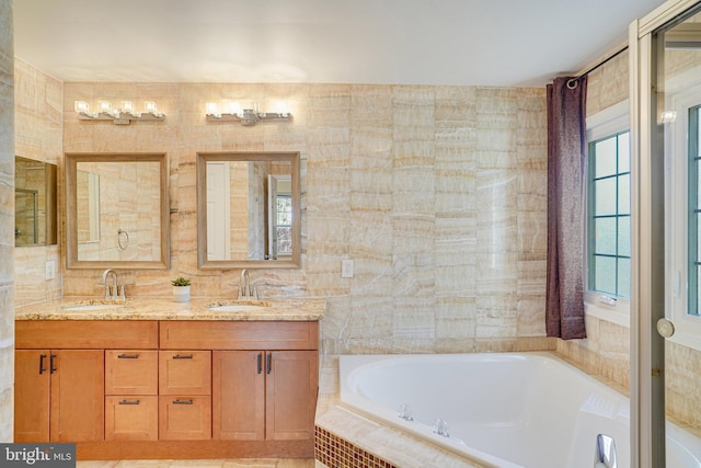 bathroom with double vanity, a sink, a bath, and tile walls