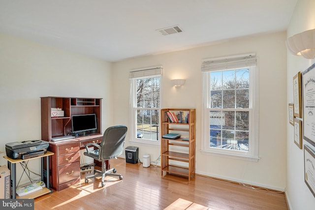 office space featuring light wood-type flooring, visible vents, and a healthy amount of sunlight